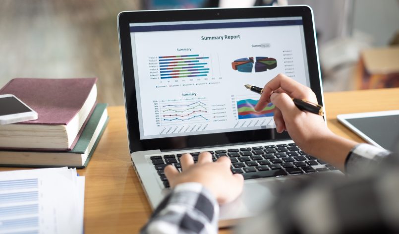 Business woman analyzing investment charts on laptop screen at morning time.